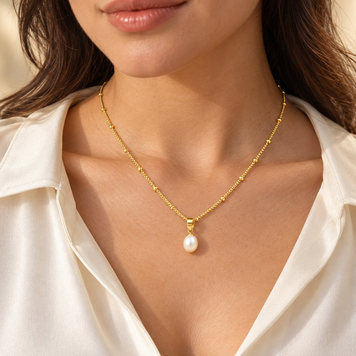 Collier doré avec perle d’eau douce porté par une femme