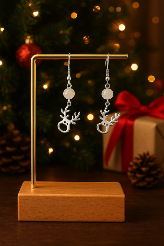 Paire de boucles d’oreilles en forme de petit renne, fabriquées avec des perles de cristal mat et des apprêts en acier inoxydable hypoallergénique, présentées sur un fond neutre.