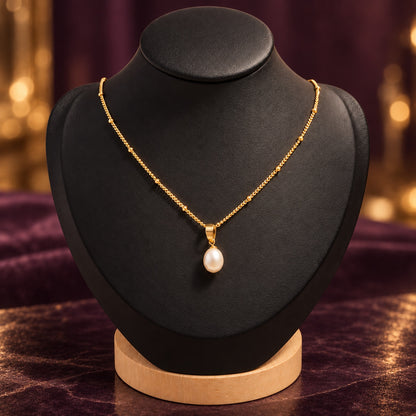 Collier doré avec perle d’eau douce sur présentoir noir, fond chic