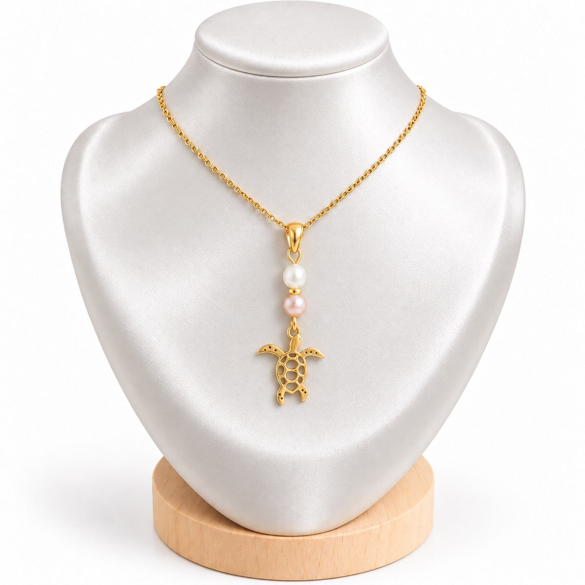 Collier tortue doré avec perles d’eau douce blanche et rosée sur présentoir blanc satiné