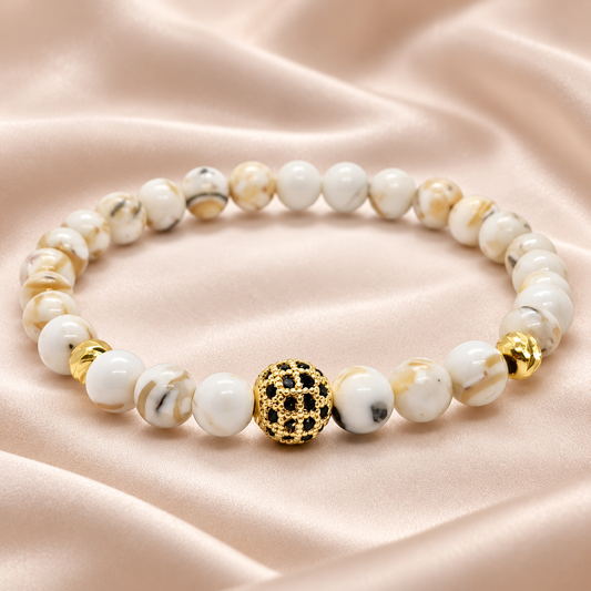 Bracelet Pureté en perles blanches et crème, détail doré, sur satin beige rosé